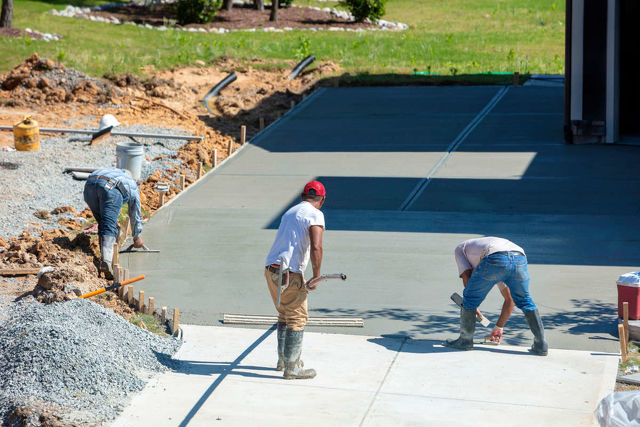 People Pouring and Evening New Concrete Driveway